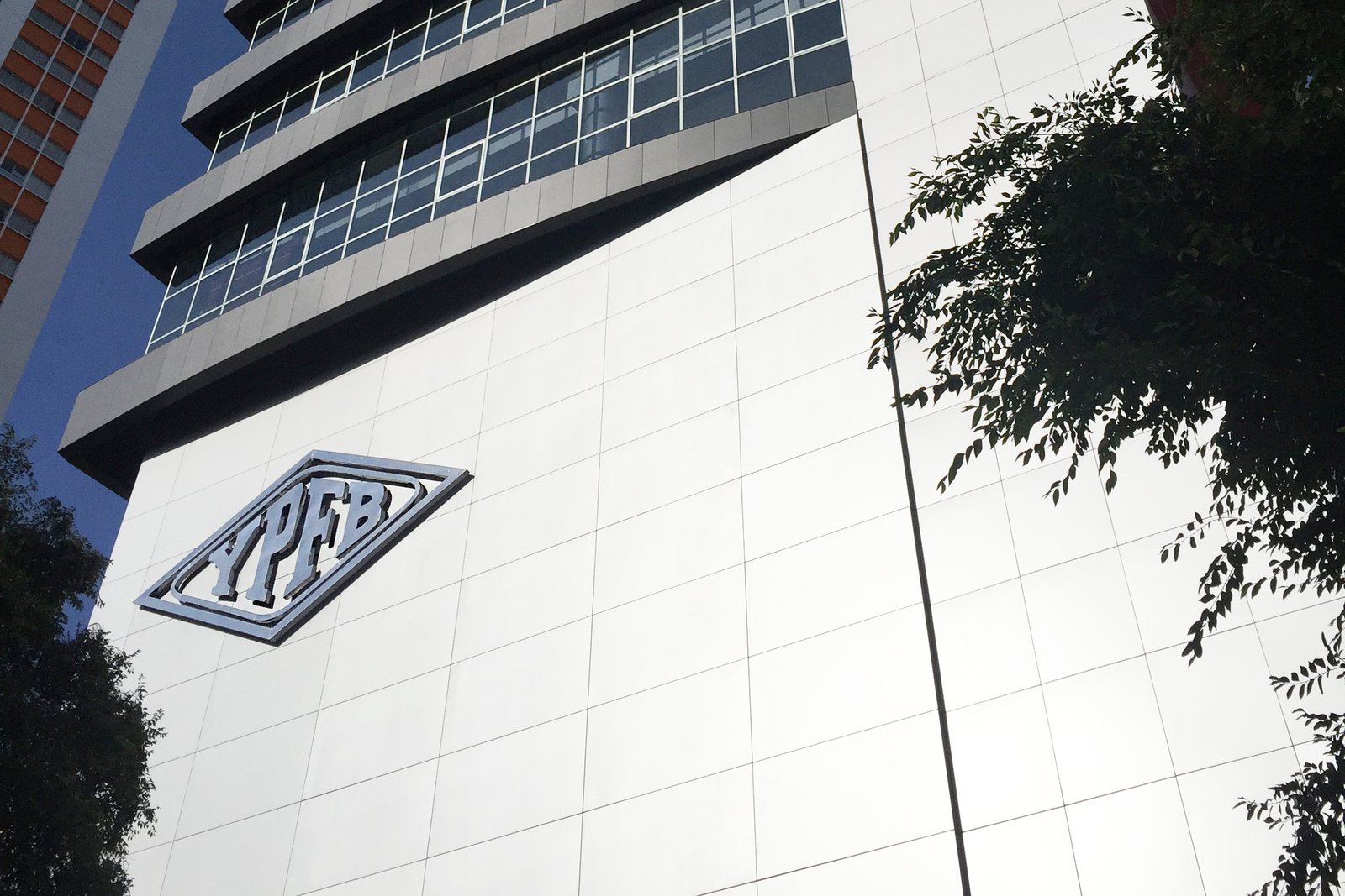 The YPFB logo on the white facade of the state oil company headquarters tower in La Paz