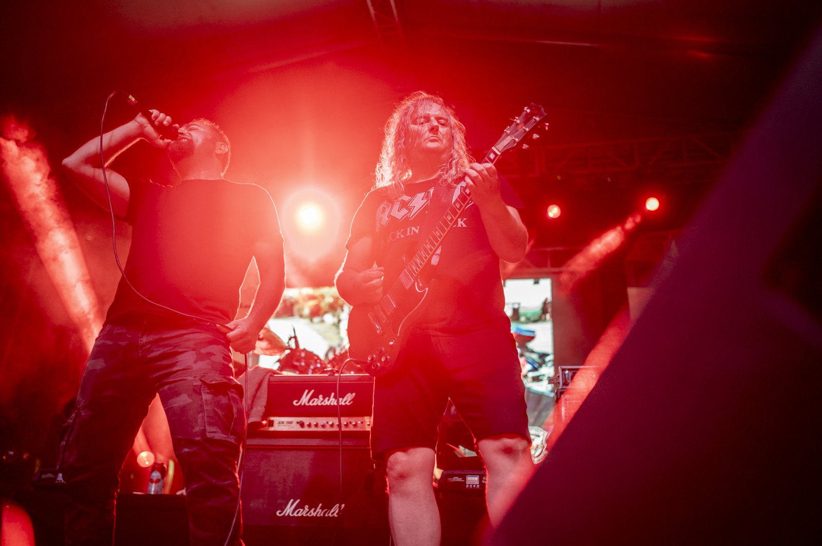 A rock band performs under dramatic red lighting.