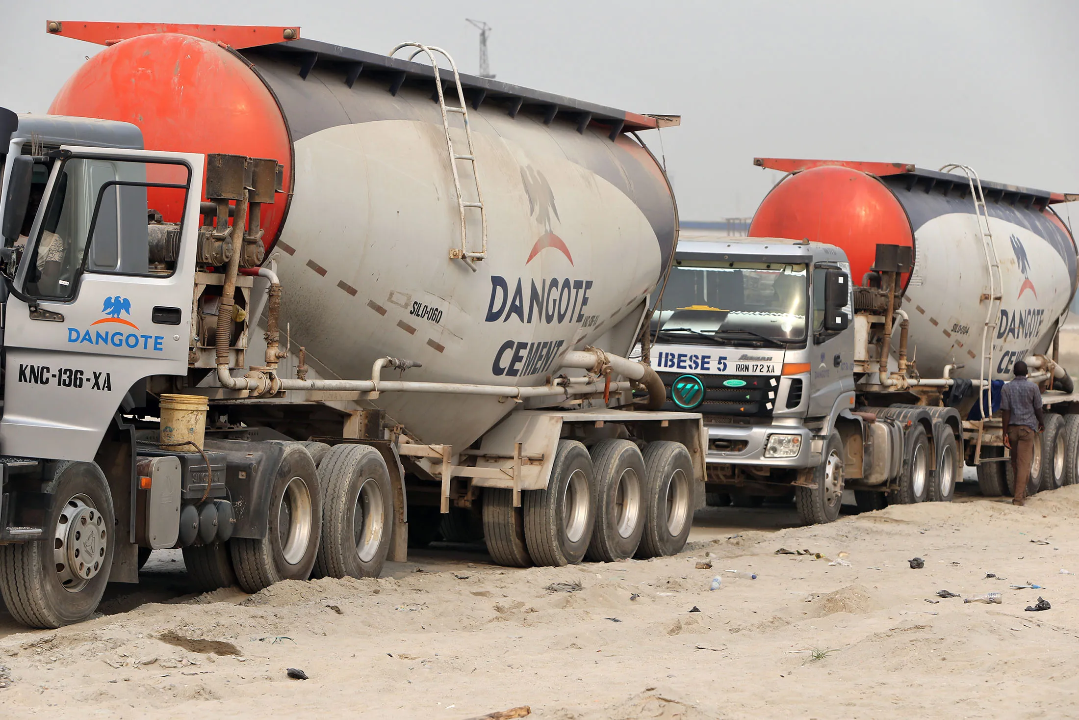 Dangote Cement truck parked at a plant, with factory silos in the background.