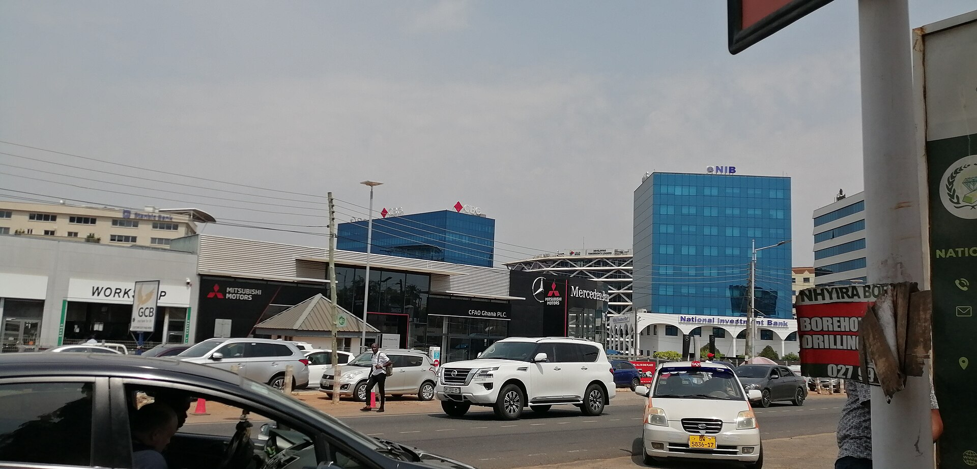 Street in Accra with a National Investment Bank office building and car dealerships