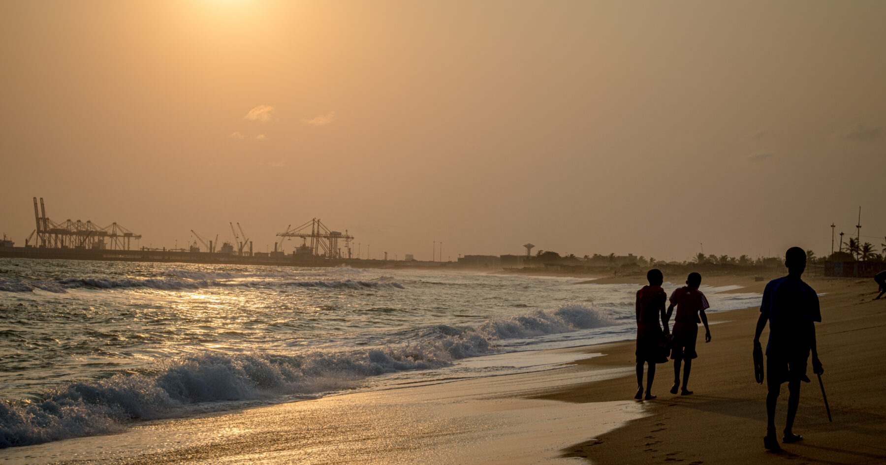 The Lome shoreline at sunset with the port cranes beyond (Philip Nalangan, CC BY 4.0, via Wikimedia Commons)