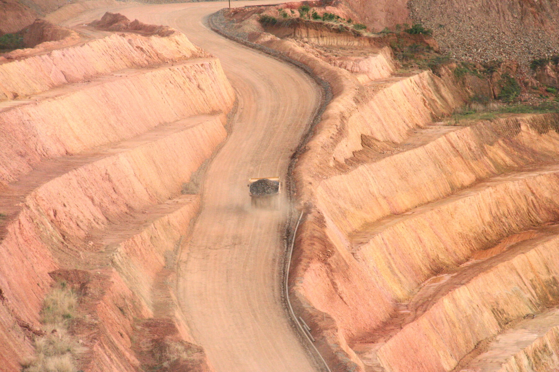 Truck hauling ore from the Karta pit, Societe Miniere de Dinguiraye, Guinea (darrylkeith, CC BY-SA 3.0, via Wikimedia Commons)