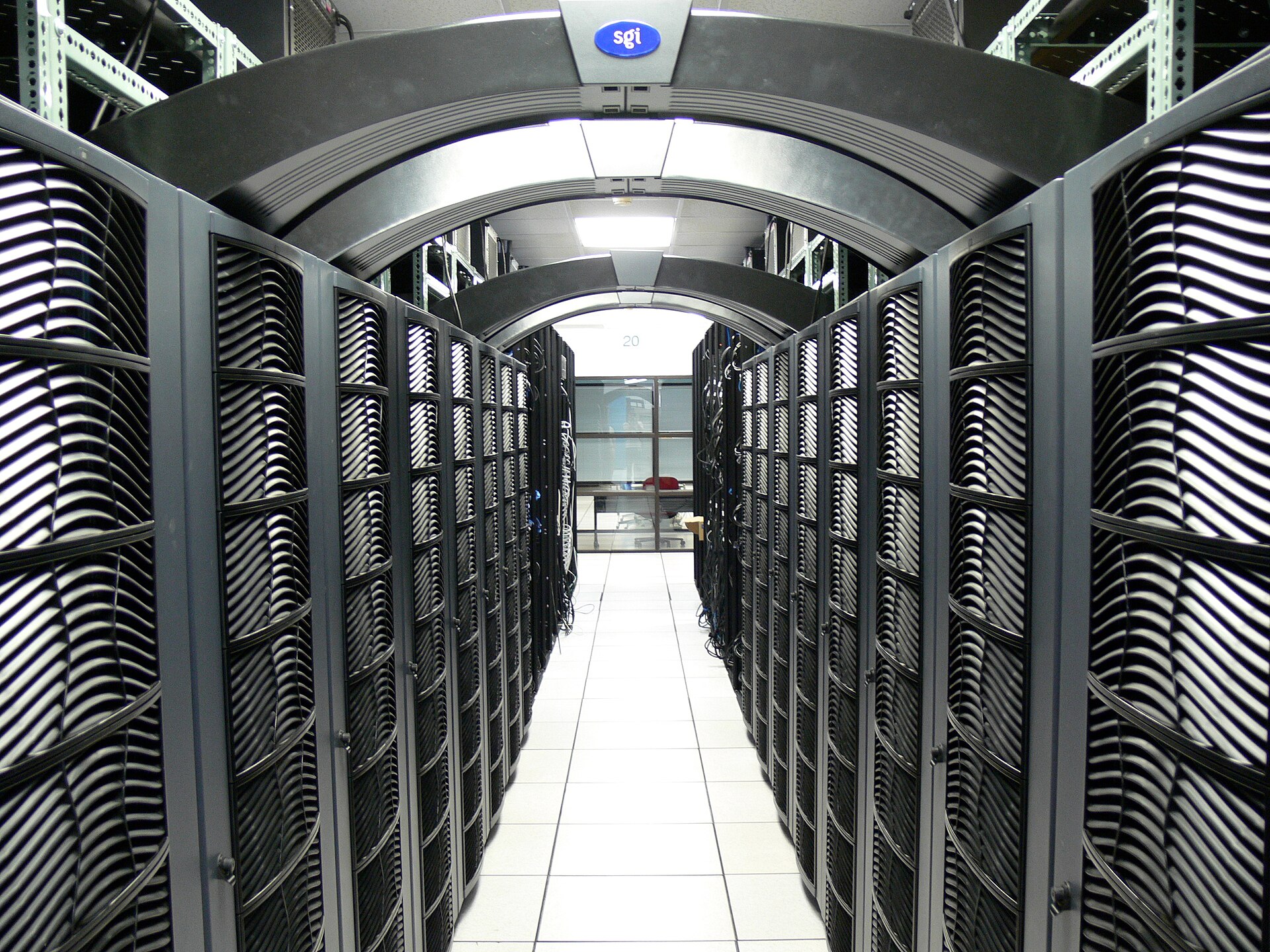 Rows of server racks along a lit aisle in a data centre.