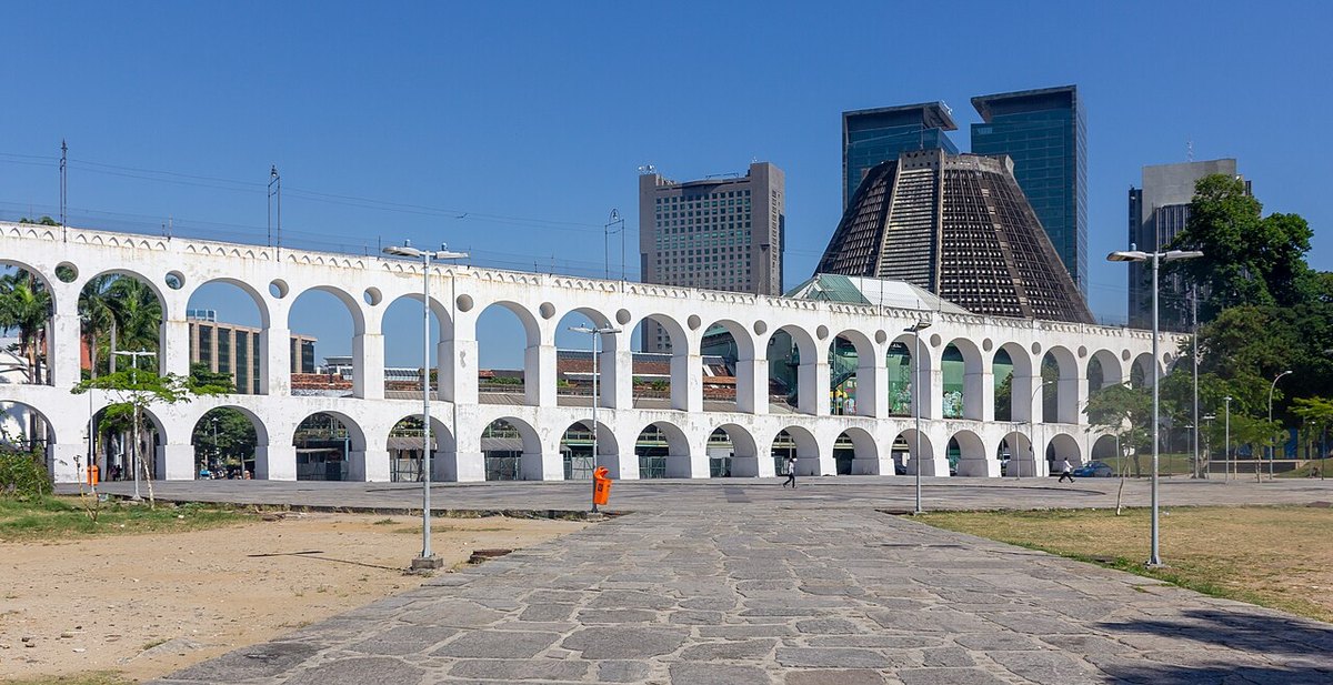 The white double-tier arches of the Arcos da Lapa aqueduct, with the conical Metropolitan Cathedral and office towers behind