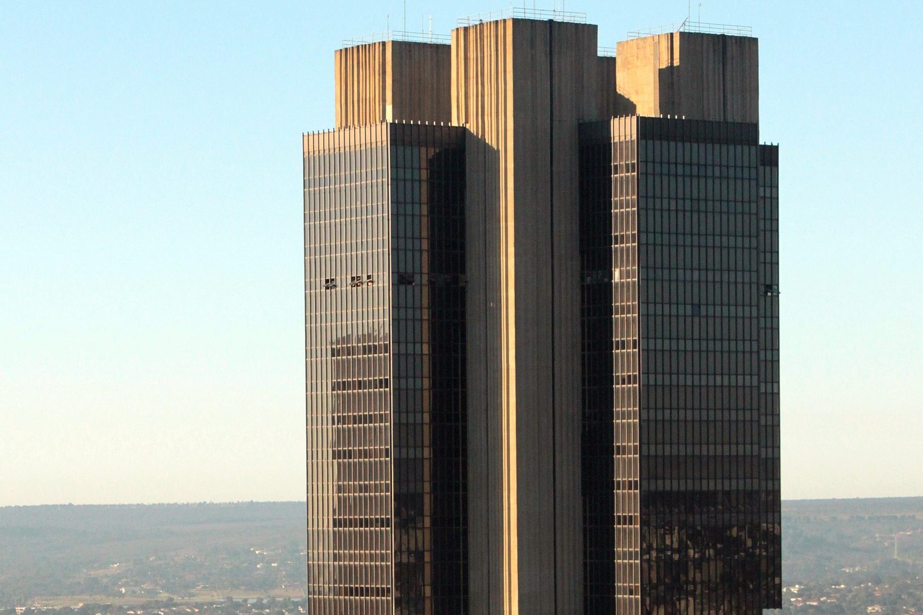 The headquarters tower of the Banco Central do Brasil in Brasília, its dark glass and concrete facade above the surrounding city.