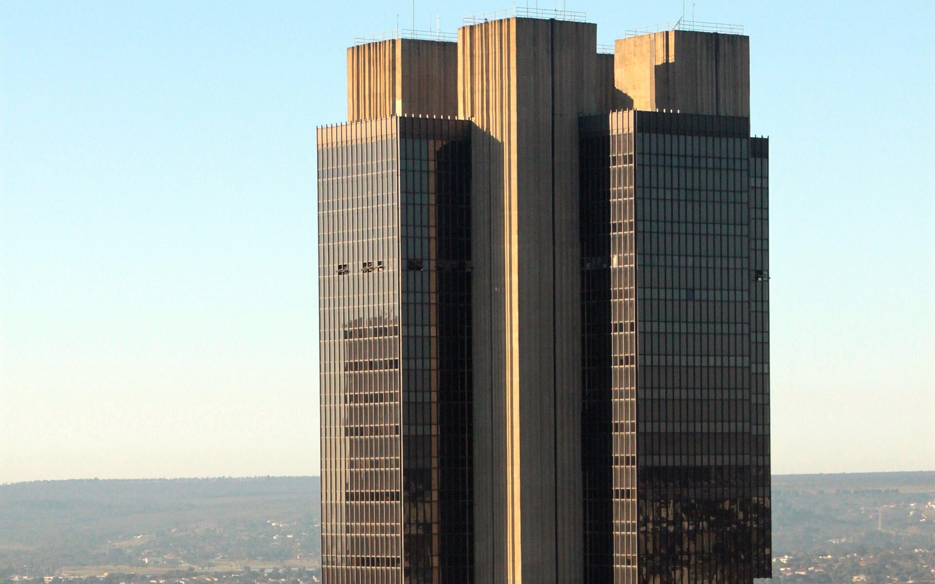 The headquarters tower of the Banco Central do Brasil in Brasília, its dark glass and concrete facade above the surrounding city.