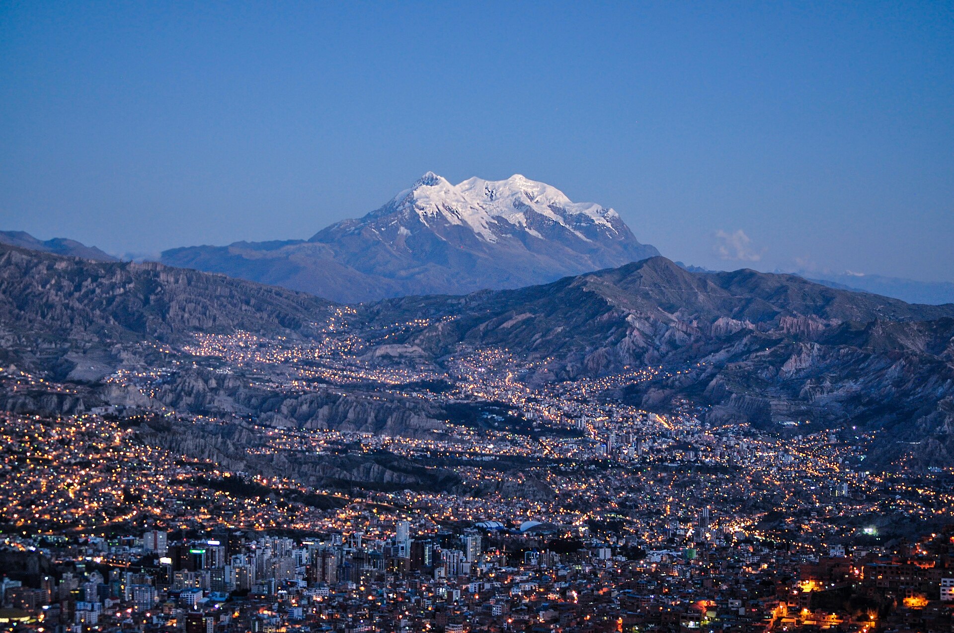Bolivia explained 2026 — La Paz at dusk seen from El Alto, with the snow-capped Illimani behind
