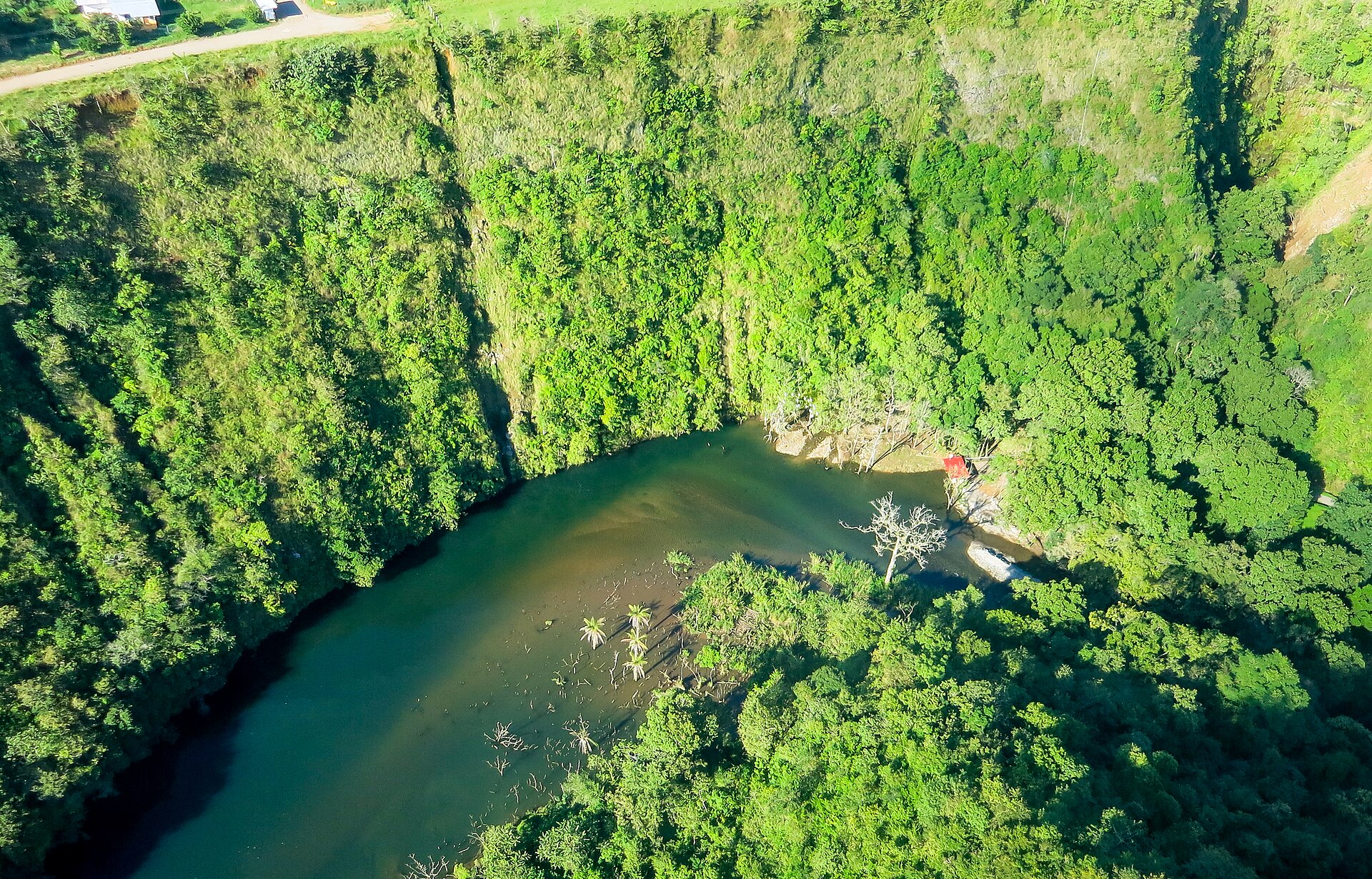 Aerial view of a forested river gorge in Chiriqui province, Panama, with steep green slopes above a brown river.