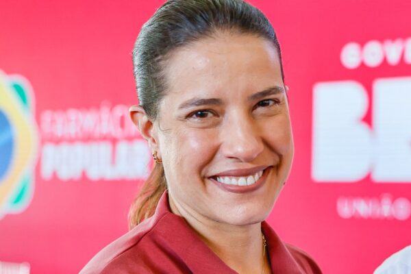 Pernambuco governor Raquel Lyra smiling at a public event in Recife in front of a red backdrop