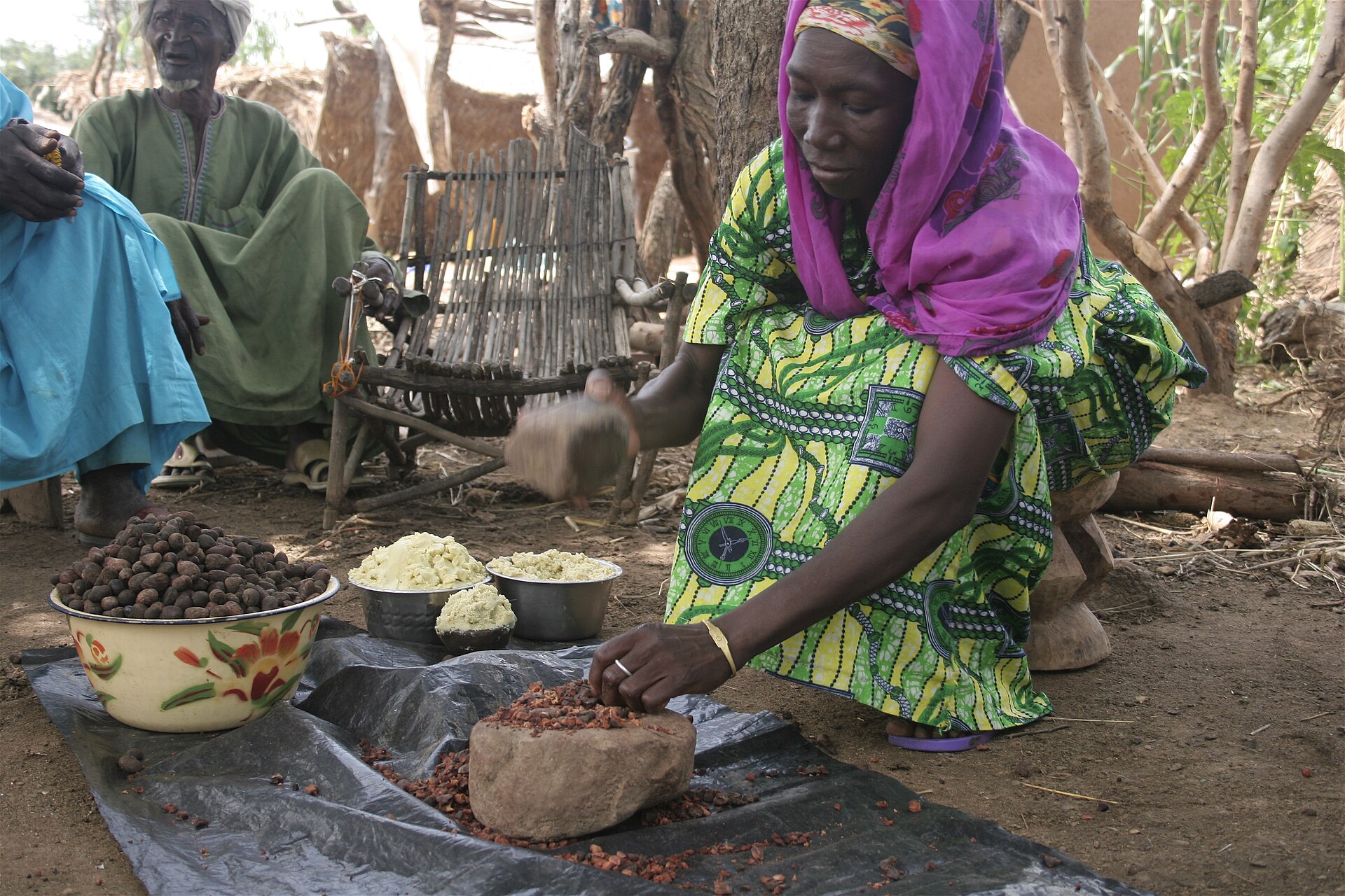 Burkina Faso explained — a woman crushing shea nuts to make shea butter