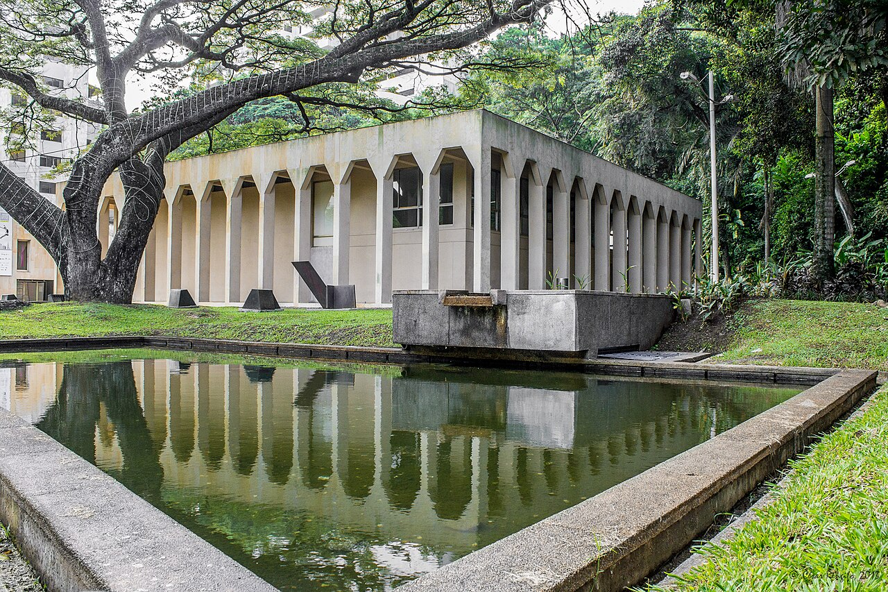 Exterior view of the Museo La Tertulia modern art museum in Cali, a low concrete building with columned walkway reflected in a pool
