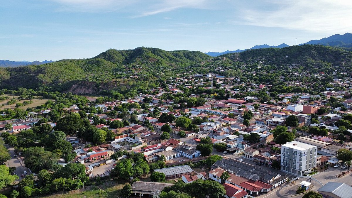 An aerial view of the Bolivian town of Camiri, with low red-roofed houses spread between green hills