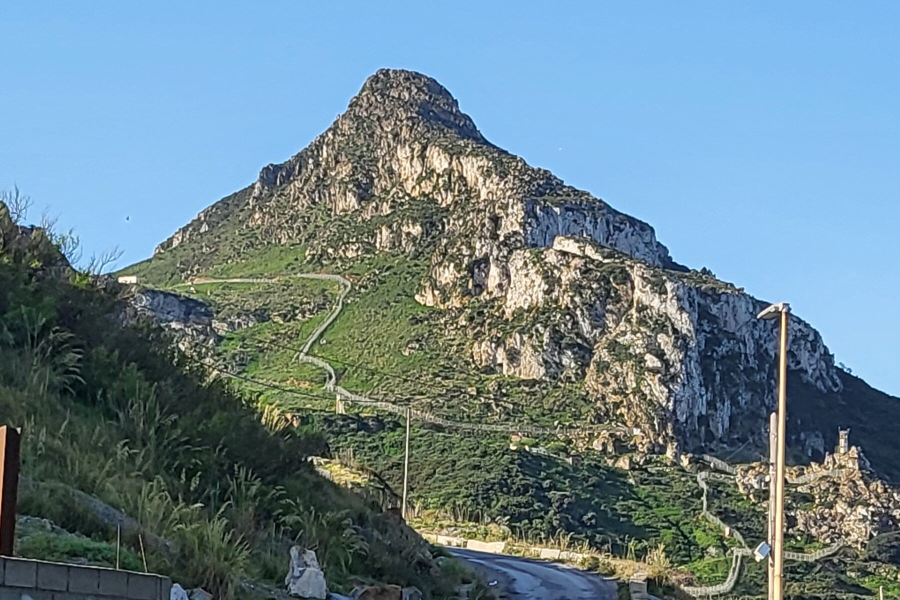 Mountain with a fence, road, and some buildings