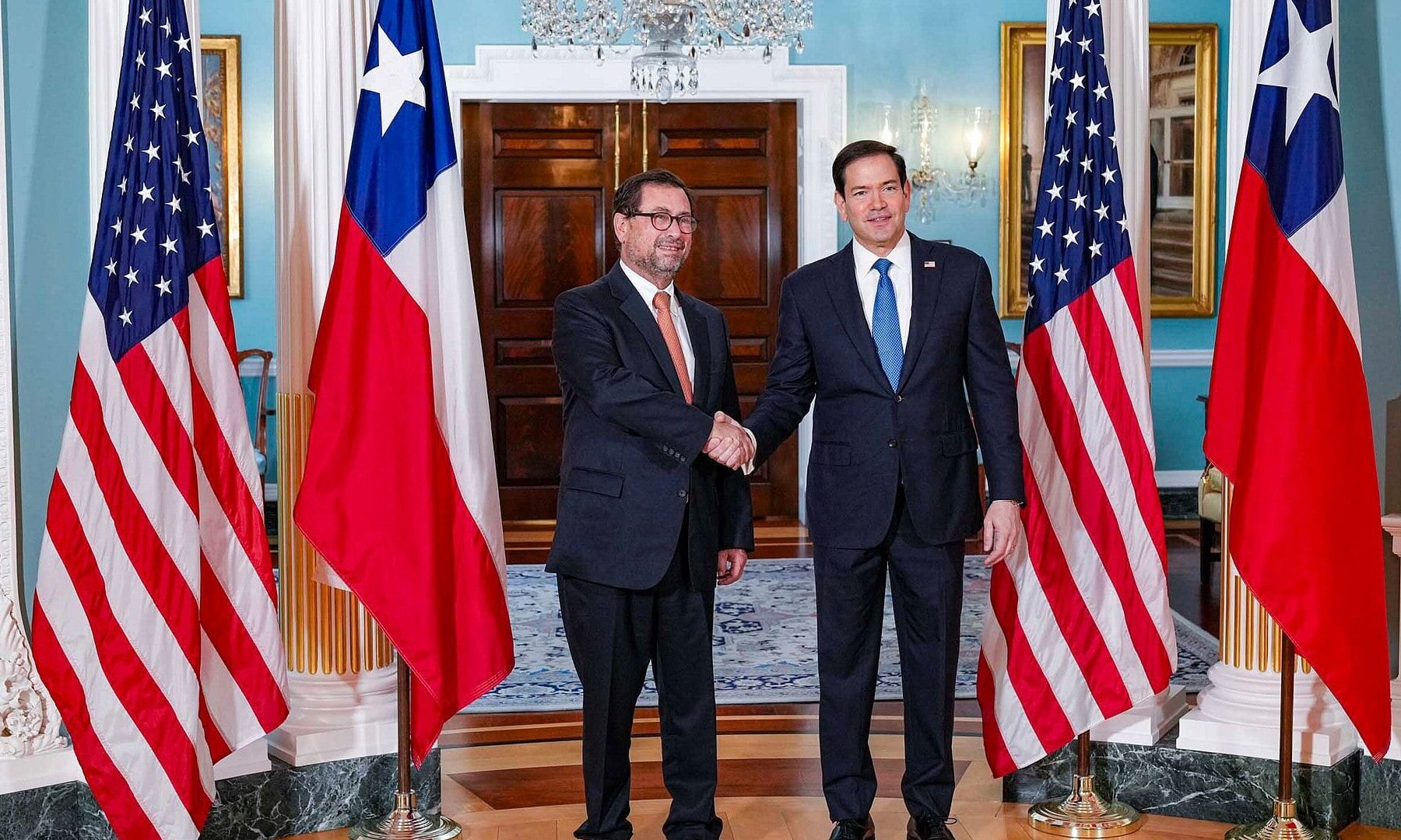 Chile foreign minister interpellation: Francisco Pérez Mackenna shakes hands with US Secretary of State Marco Rubio between Chilean and US flags at the State Department