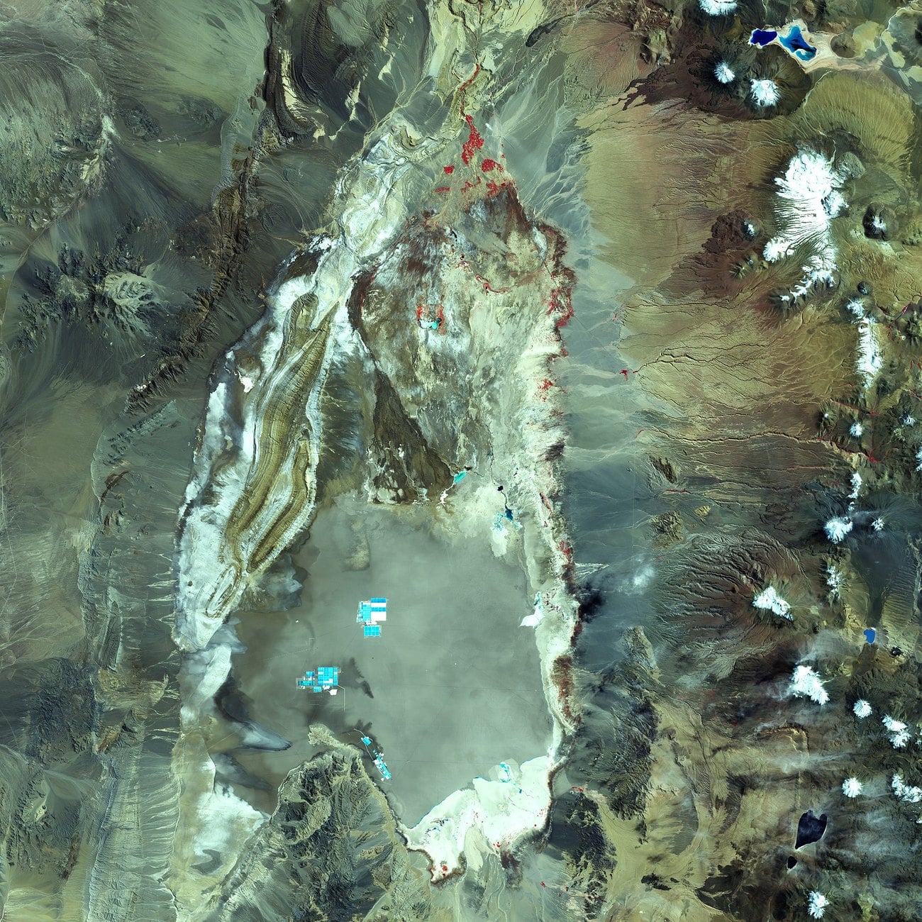 A satellite view of the Salar de Atacama in Chile, with bright turquoise evaporation ponds on the pale salt flat