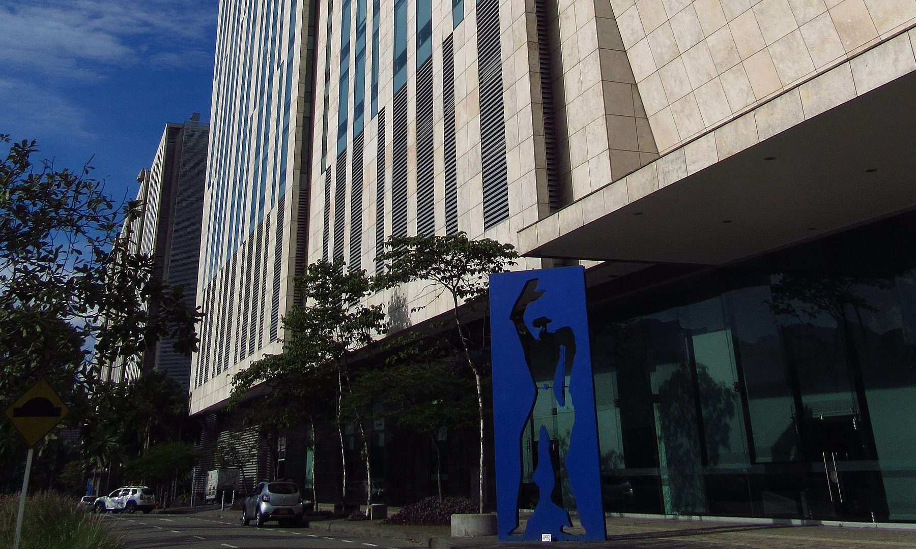 Bancolombia headquarters in Medellín's Ciudad del Río district, with a blue sculpture at the entrance; its parent Grupo Cibest cut the Colombia 2027 growth forecast