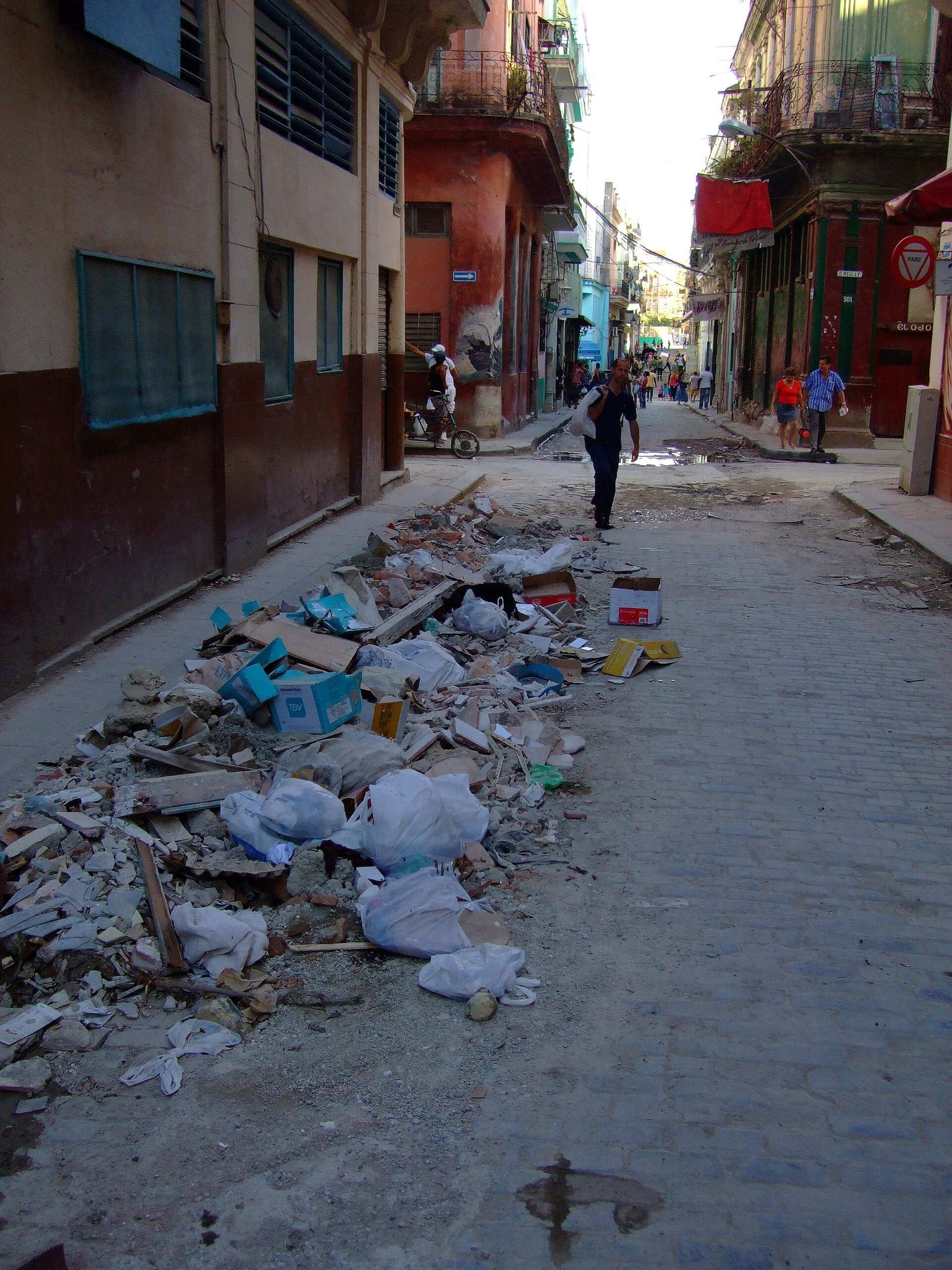 A narrow street in Old Havana, Cuba, with rubbish piled at the roadside
