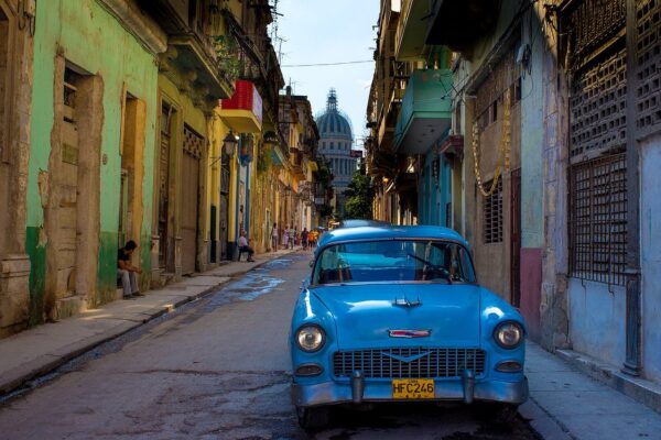 Cuba explained 2026: a vintage American car on a narrow street in Havana with the Capitolio dome behind