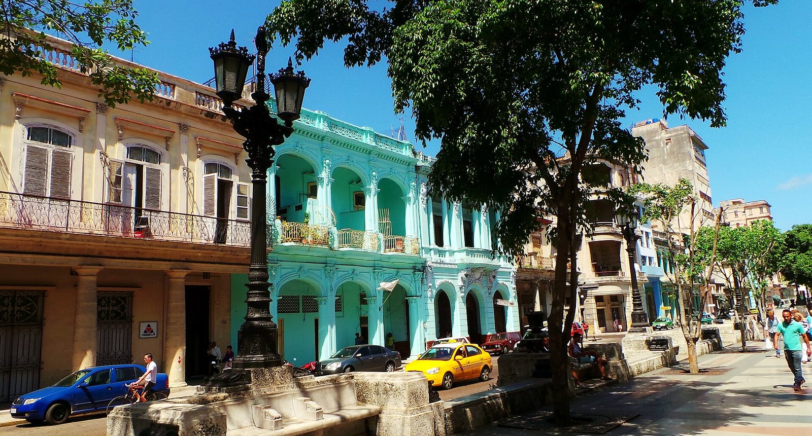A colonnaded street in central Havana with pastel buildings and a vintage car