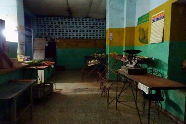 Cuba market reforms: a sparsely stocked farmers' market in Havana with empty stalls, a scale and a few vegetables