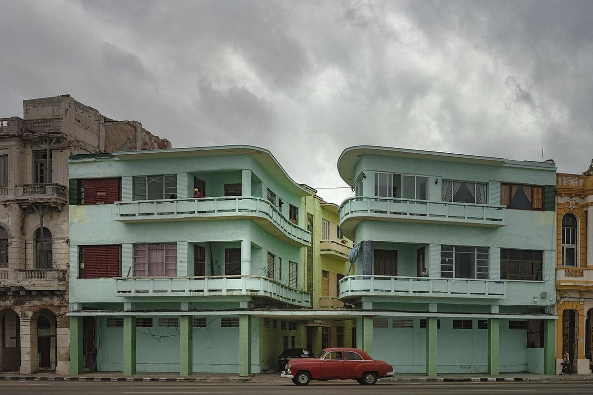 Pastel-coloured apartment buildings and a red classic car on a street in Centro Habana, Cuba