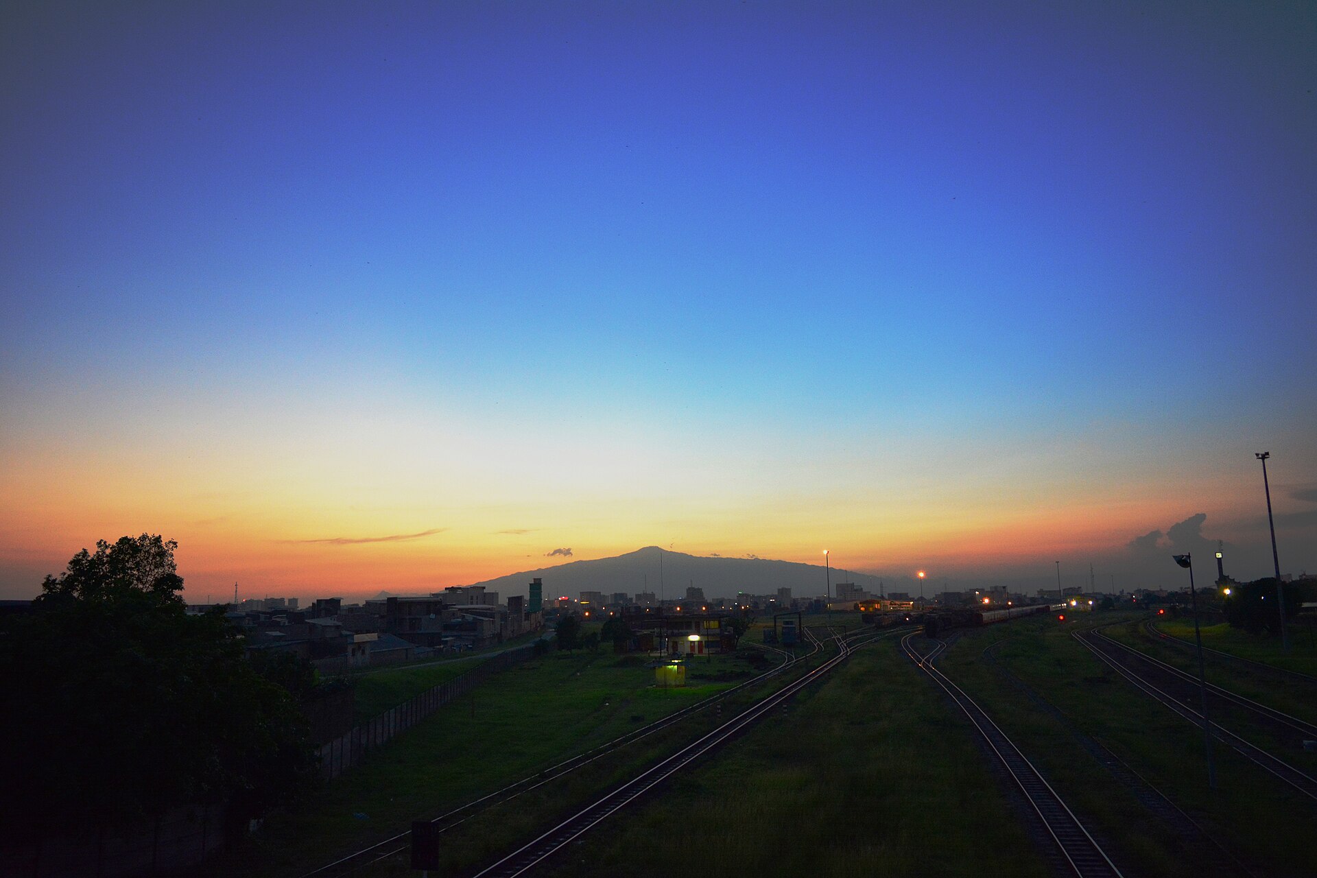 Mount Cameroon on the horizon at dusk, seen from Douala across a railway yard