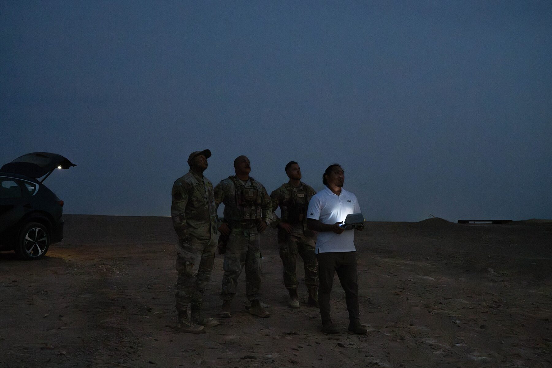 Personnel launching a small quadcopter drone at night