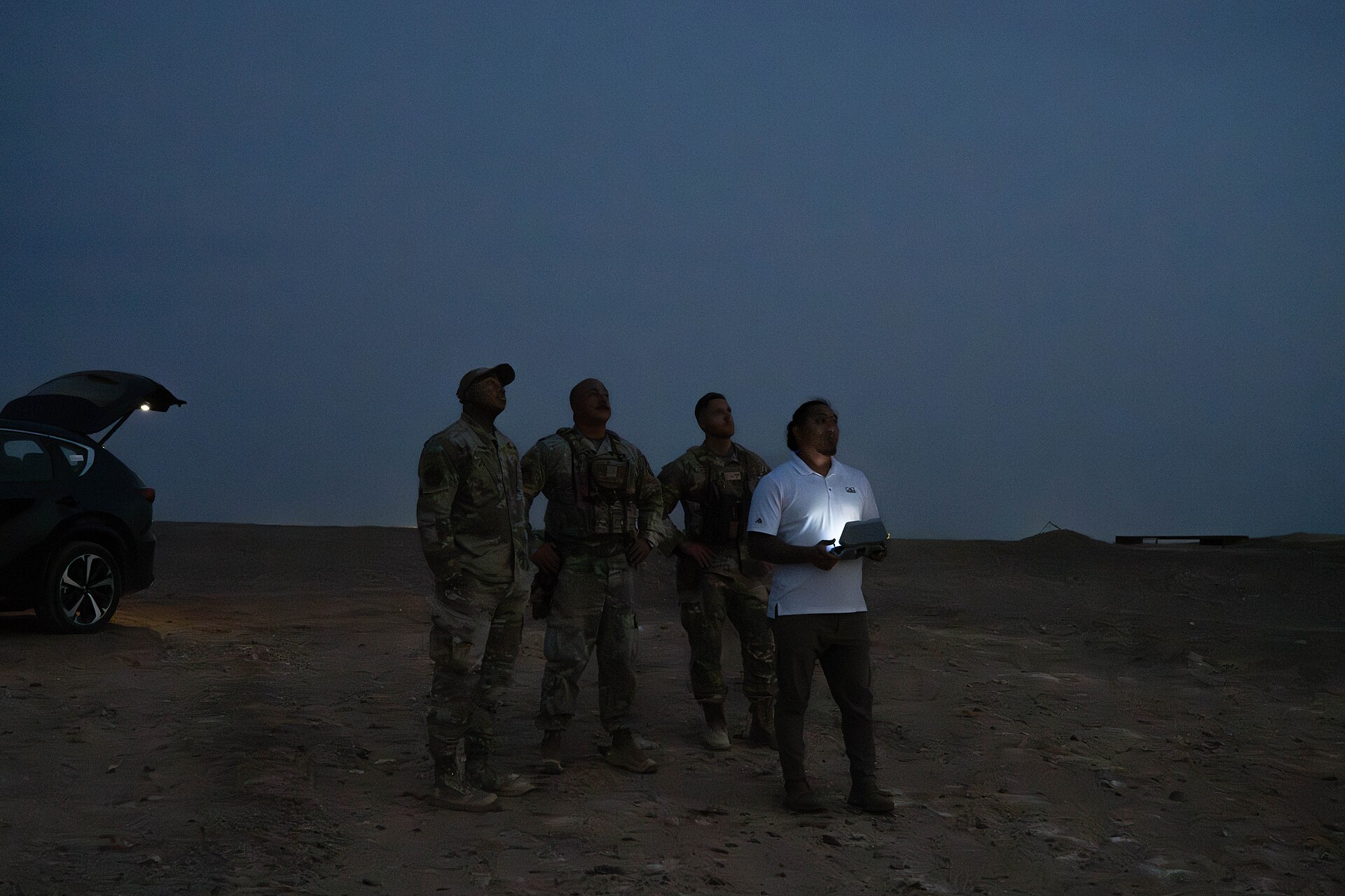 Personnel launching a small quadcopter drone at night