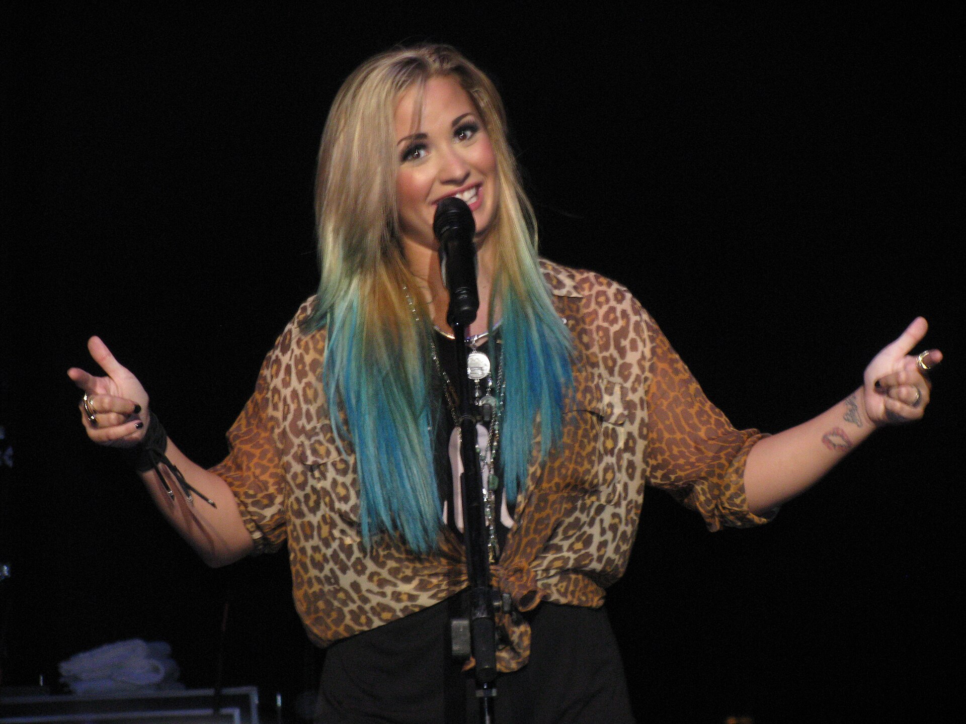 Demi Lovato performing on stage, reaching out towards her fans