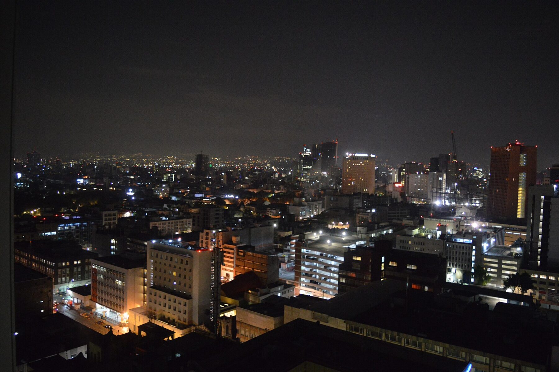Nighttime cityscape with illuminated buildings and distant lights