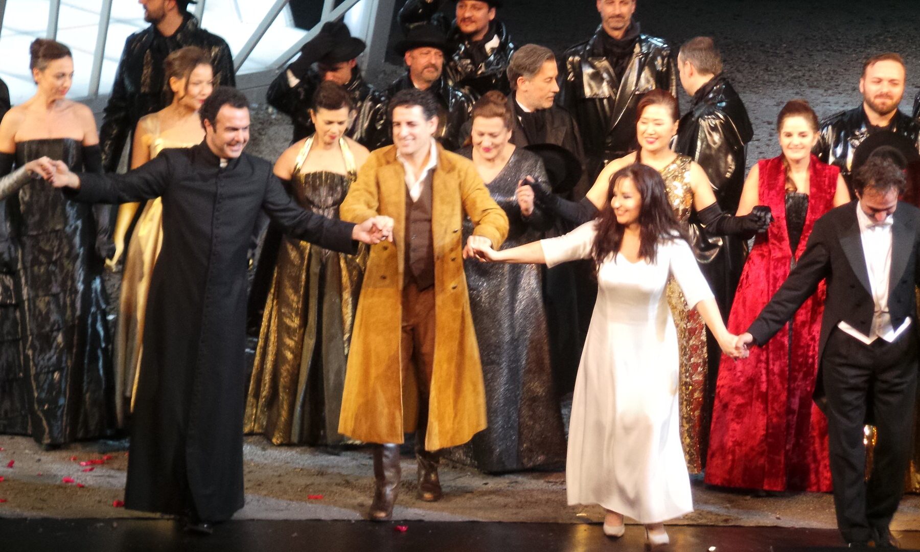 Performers on stage holding hands, bowing to audience