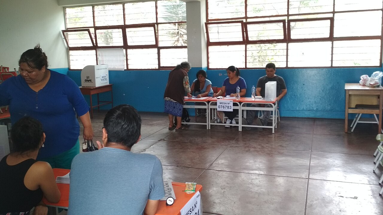 Voters and poll workers at polling tables inside a school hall in Callao, Peru