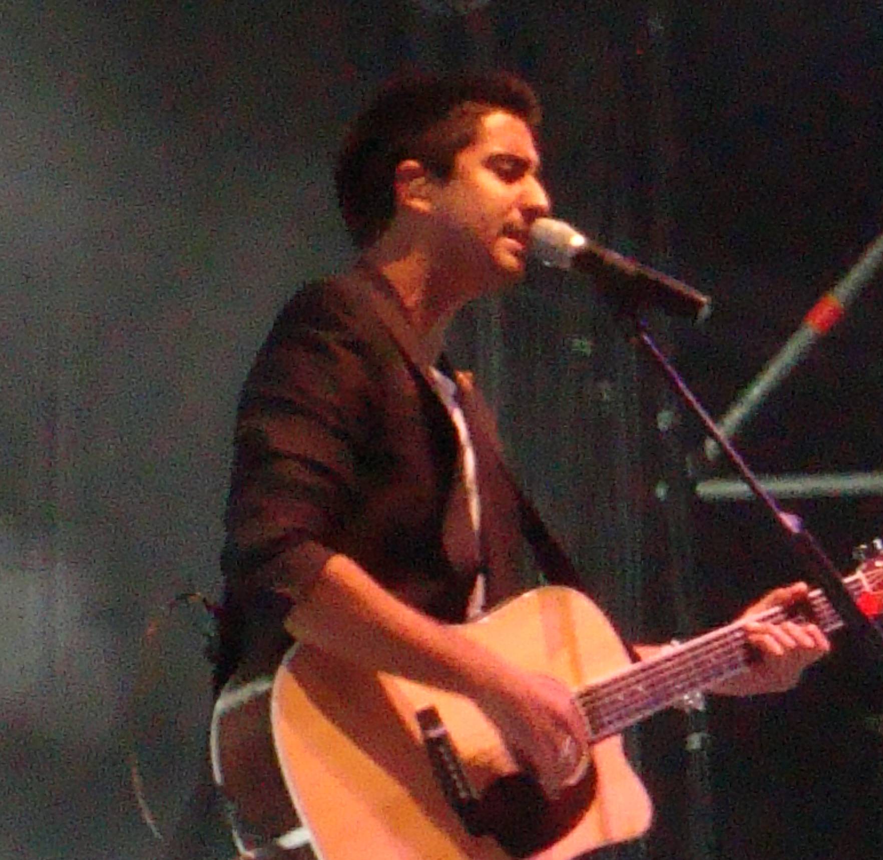 Alex Ubago performing live with guitar on stage
