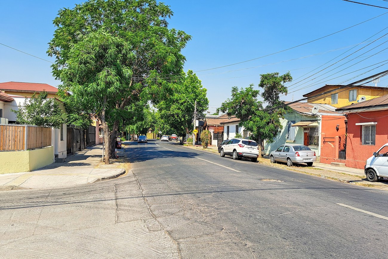 A quiet residential street in the Independencia district of Santiago, Chile, with low houses and parked cars.