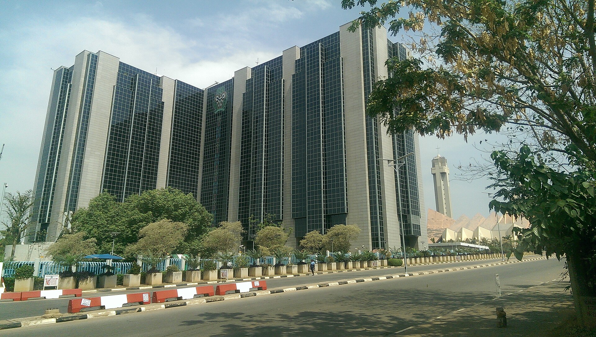 The Central Bank of Nigeria headquarters building in Abuja, seen from a tree-lined avenue.