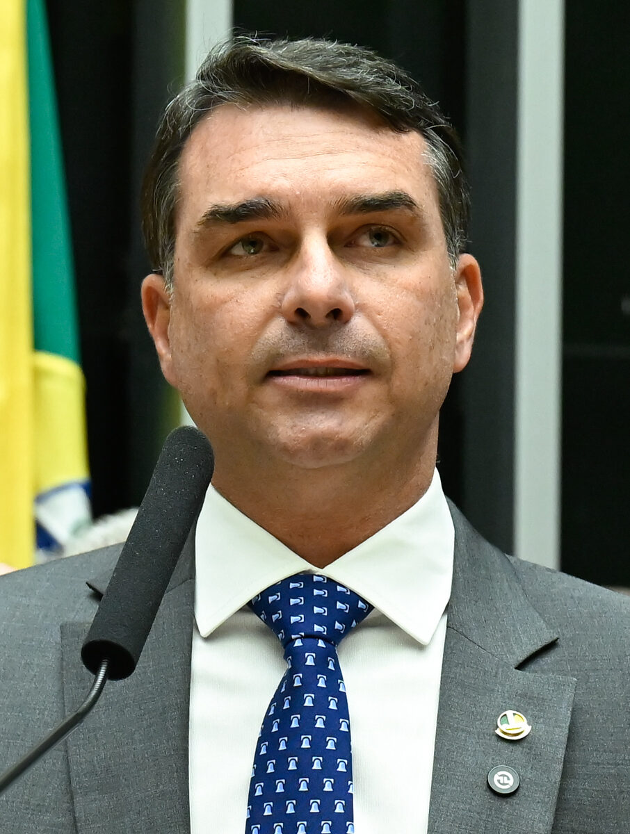 Senator Flavio Bolsonaro speaking at a podium in Brasilia
