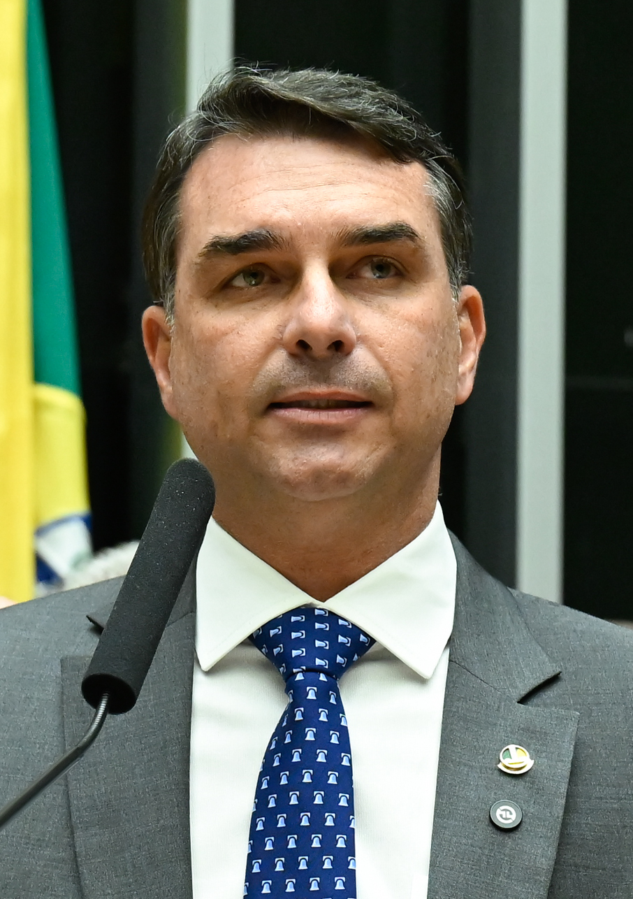 Senator Flavio Bolsonaro speaking at a podium in Brasilia