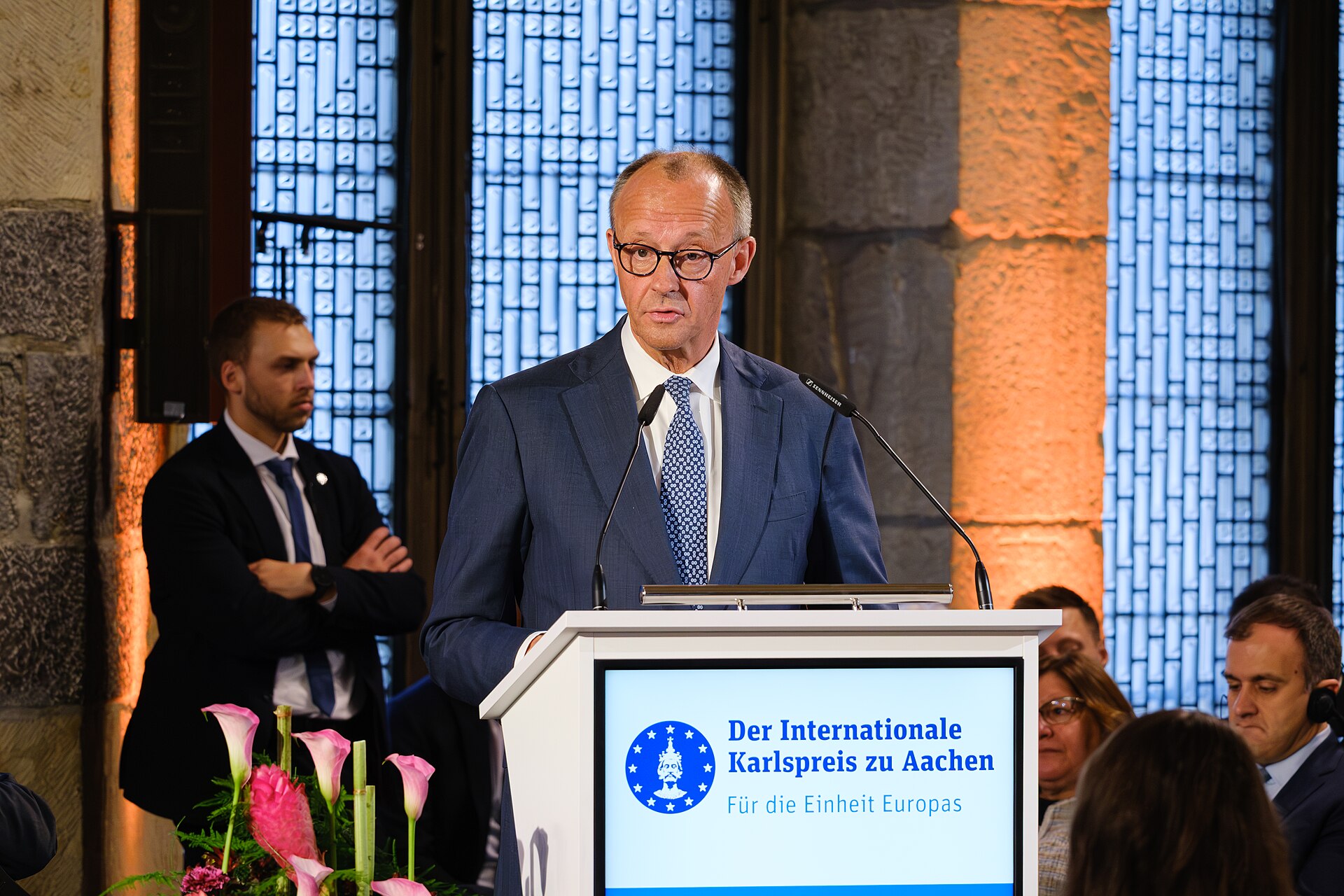 Chancellor Friedrich Merz speaking at a lectern at the Charlemagne Prize ceremony in Aachen