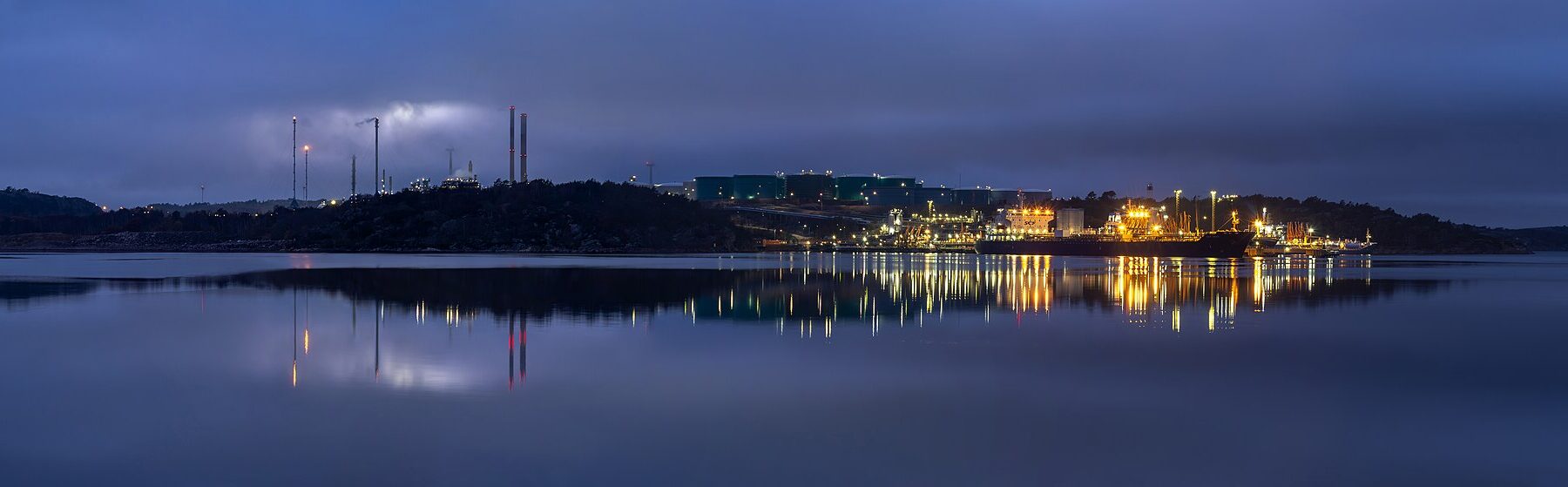 Industrial waterfront with storage tanks and ships at night