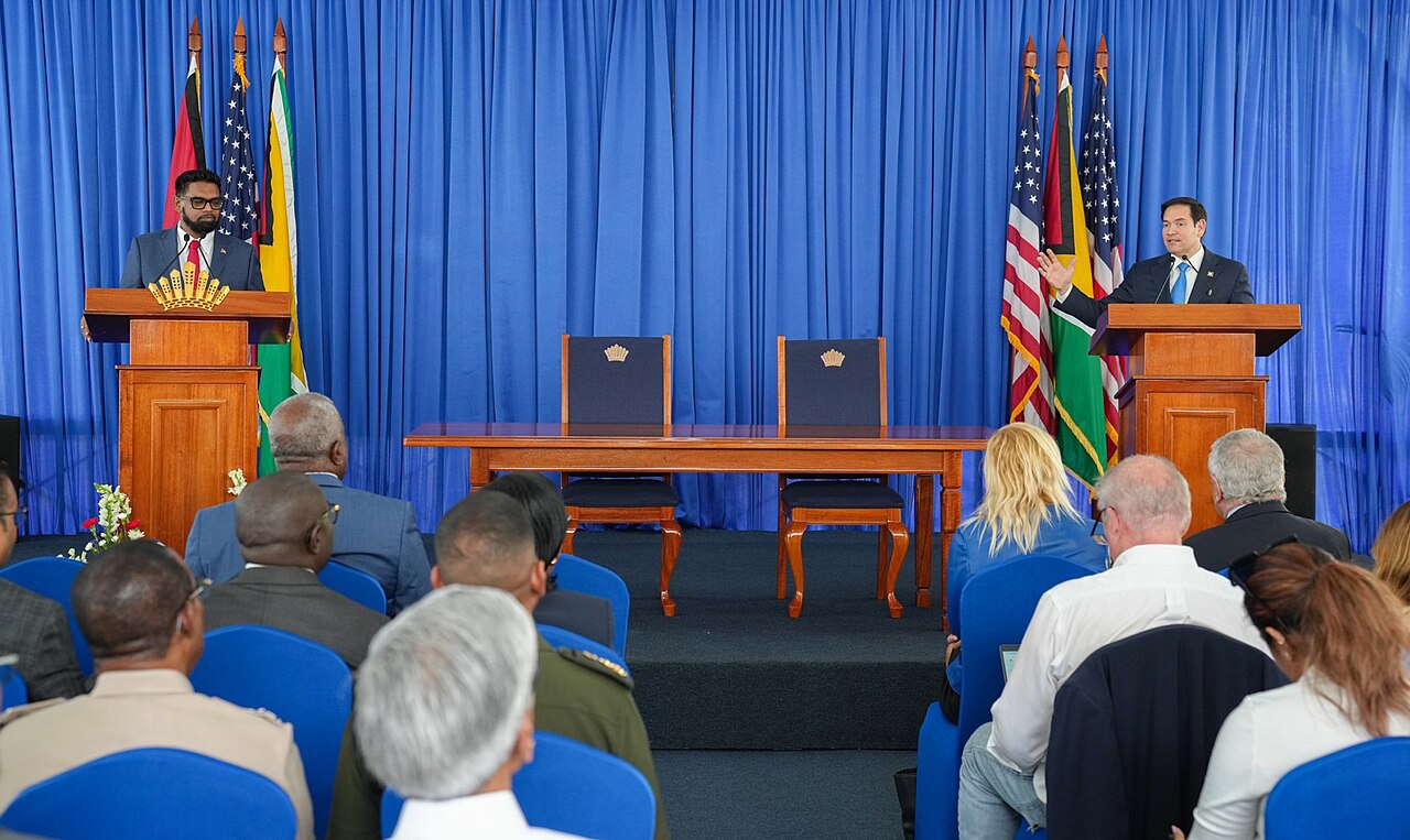 Guyana migration policy: President Irfaan Ali at a lectern during a press conference in Georgetown, with Guyanese and US flags