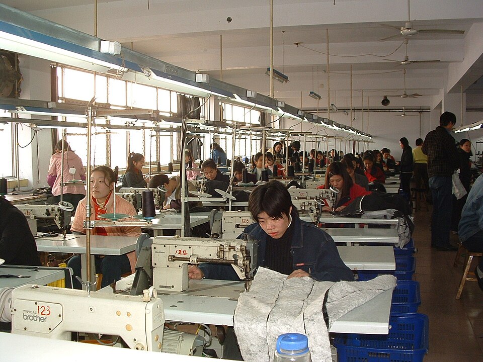 Workers at rows of sewing machines on a garment factory floor
