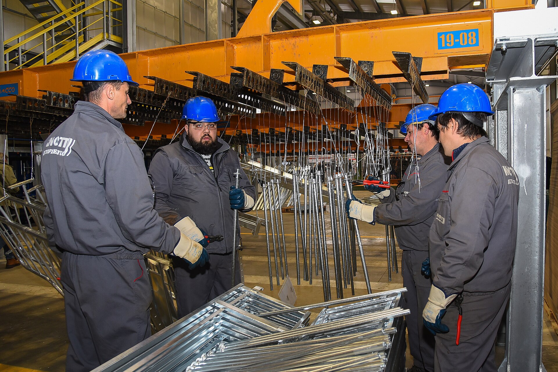 Workers handling freshly galvanised steel parts at a hot-dip galvanizing plant.