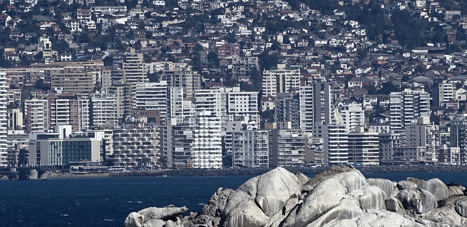 Apartment towers on the Viña del Mar waterfront in Chile, seen across the bay behind granite rocks