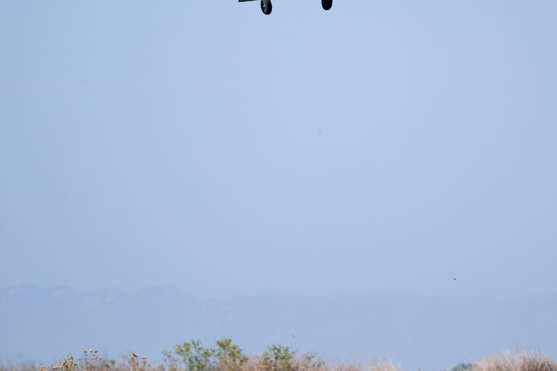 A low-flying agricultural aircraft releasing spray over a flat green field