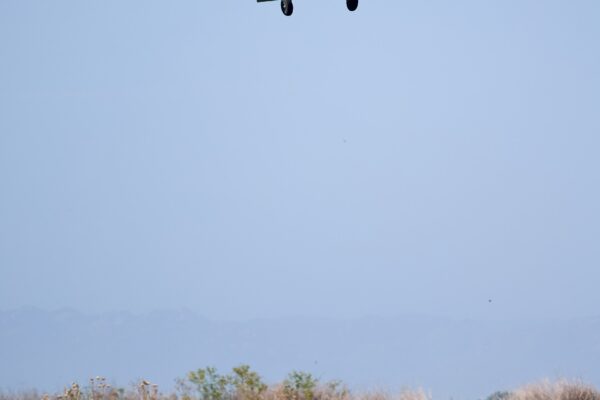 A low-flying agricultural aircraft releasing spray over a flat green field