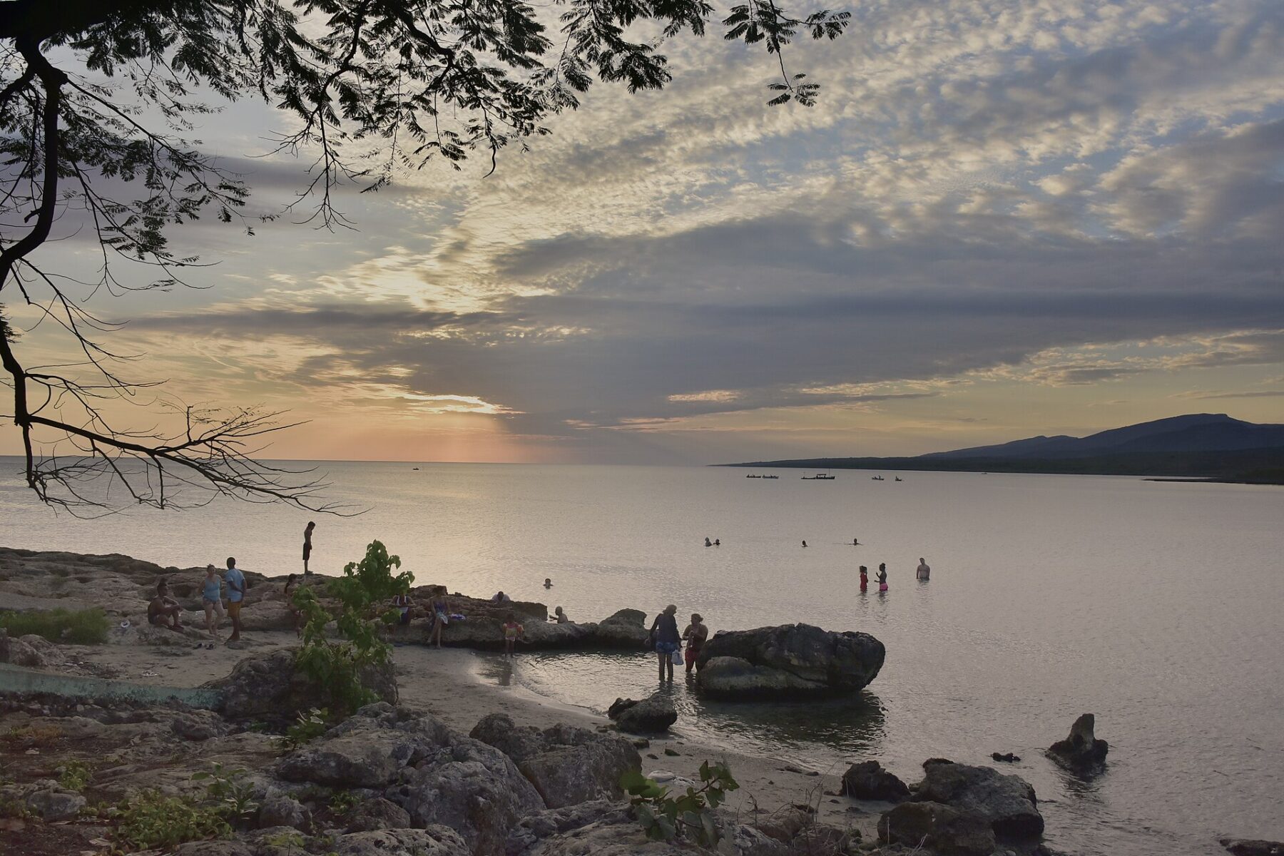 People bathing on a rocky Cuban shoreline at dusk