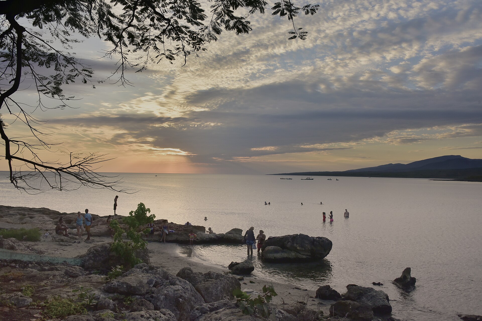 People bathing on a rocky Cuban shoreline at dusk