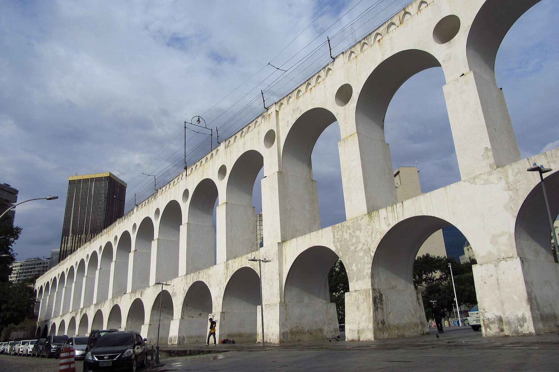 The white arches of the Lapa aqueduct in central Rio de Janeiro under a partly clouded sky