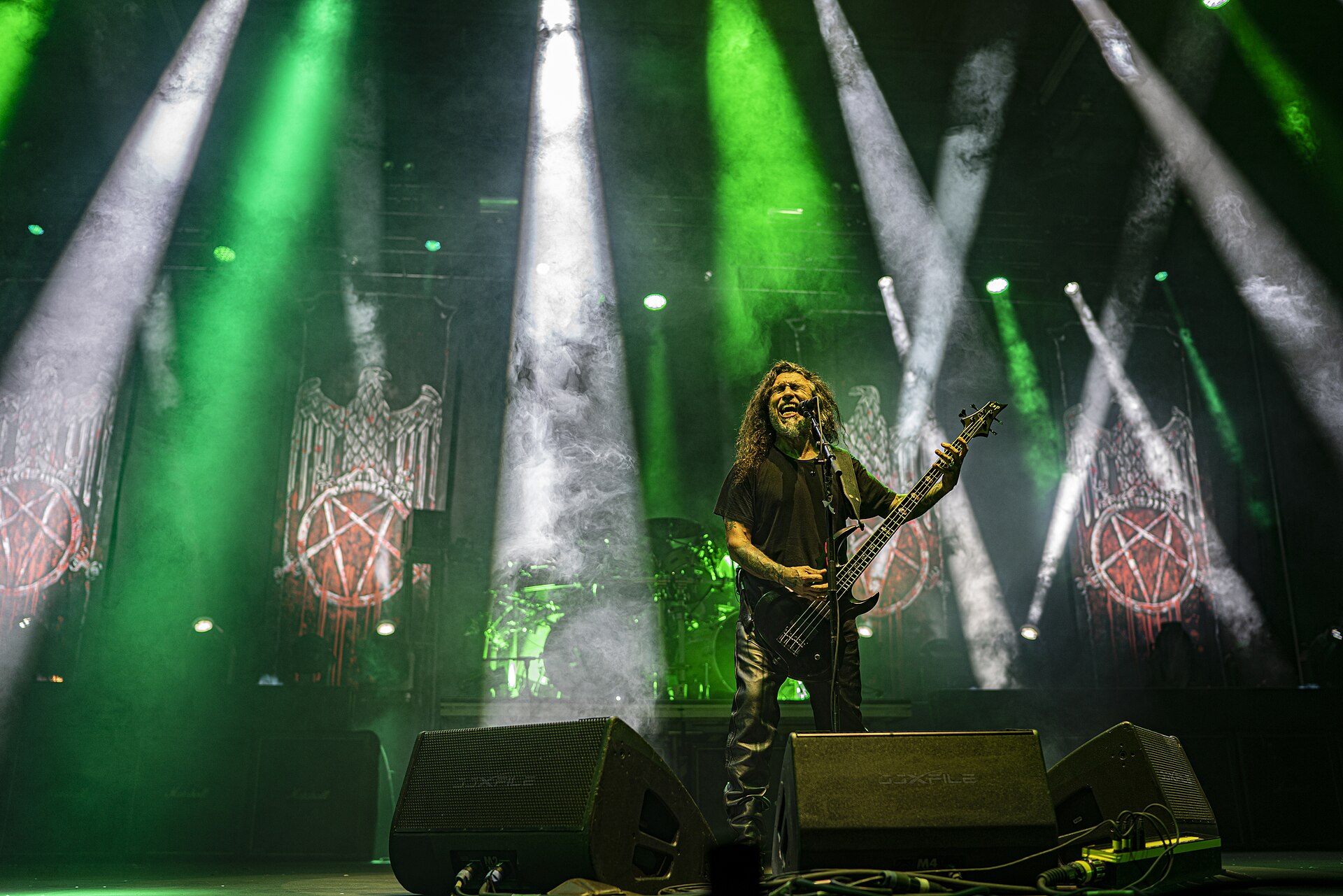 Tom Araya of Slayer performing on stage under green lights