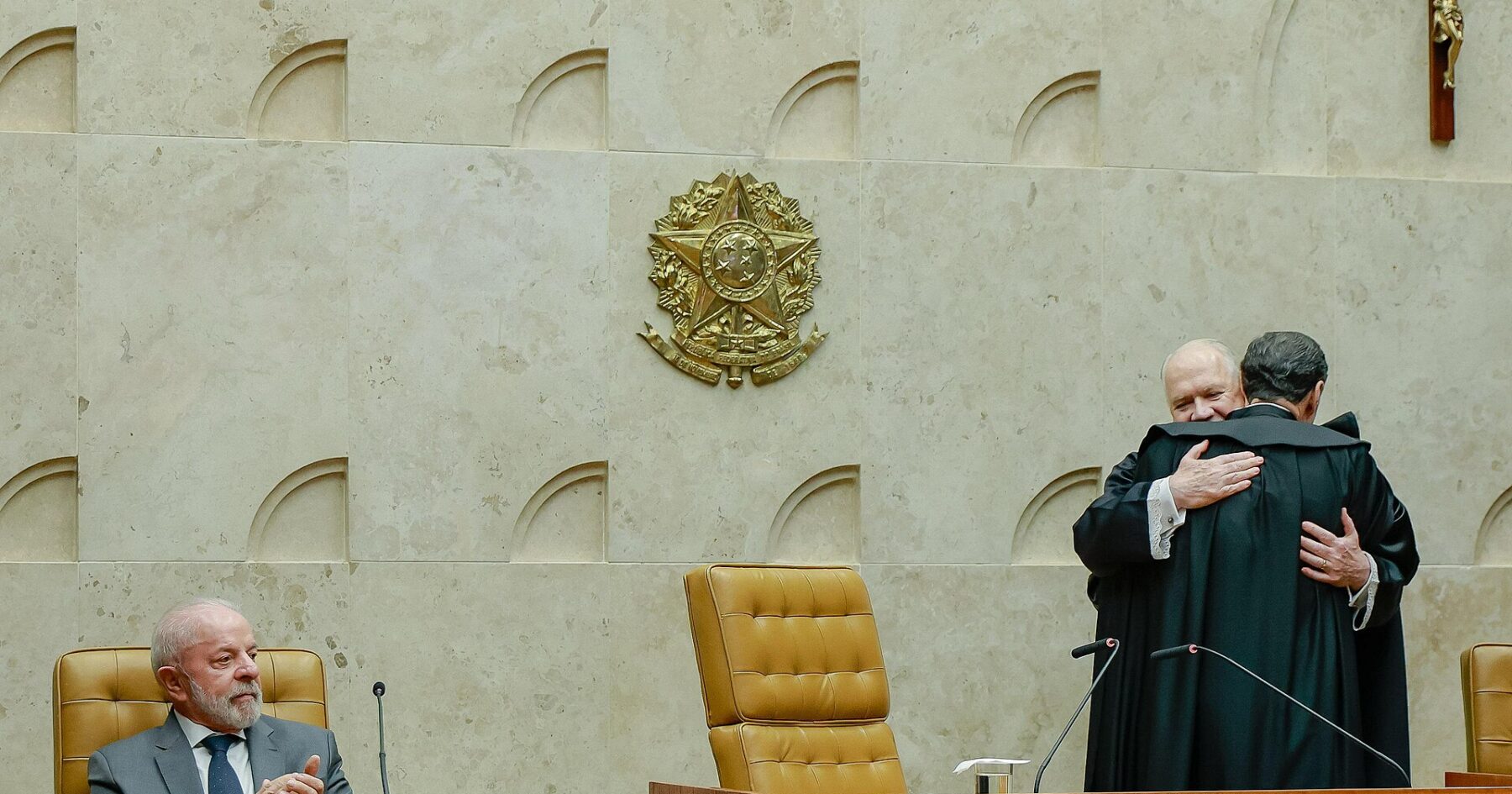 Justices in robes embrace in the plenary chamber of Brazil's Supreme Federal Court as President Lula applauds from the bench